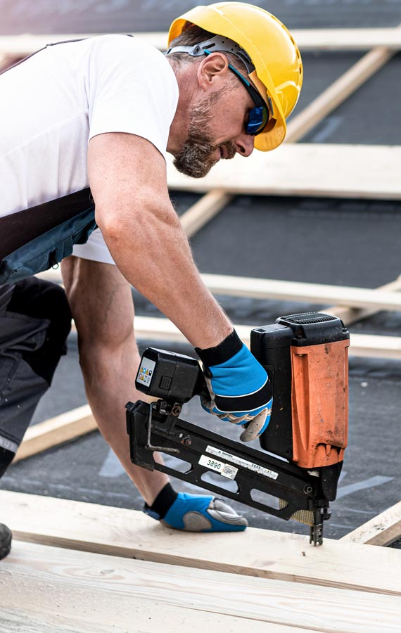 Ein Dachdecker, der an der Dachreparatur eines Hauses arbeitet.