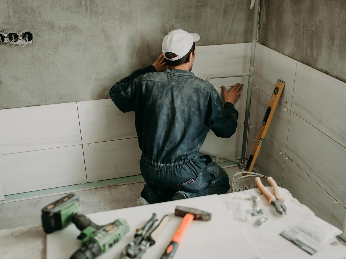 Handwerker der im Bad Fliesen anbringt